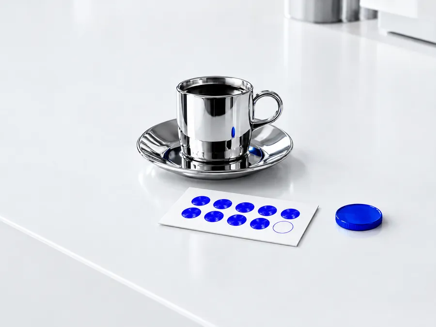 Chrome coffee cup beside a white stamp card with blue stamps